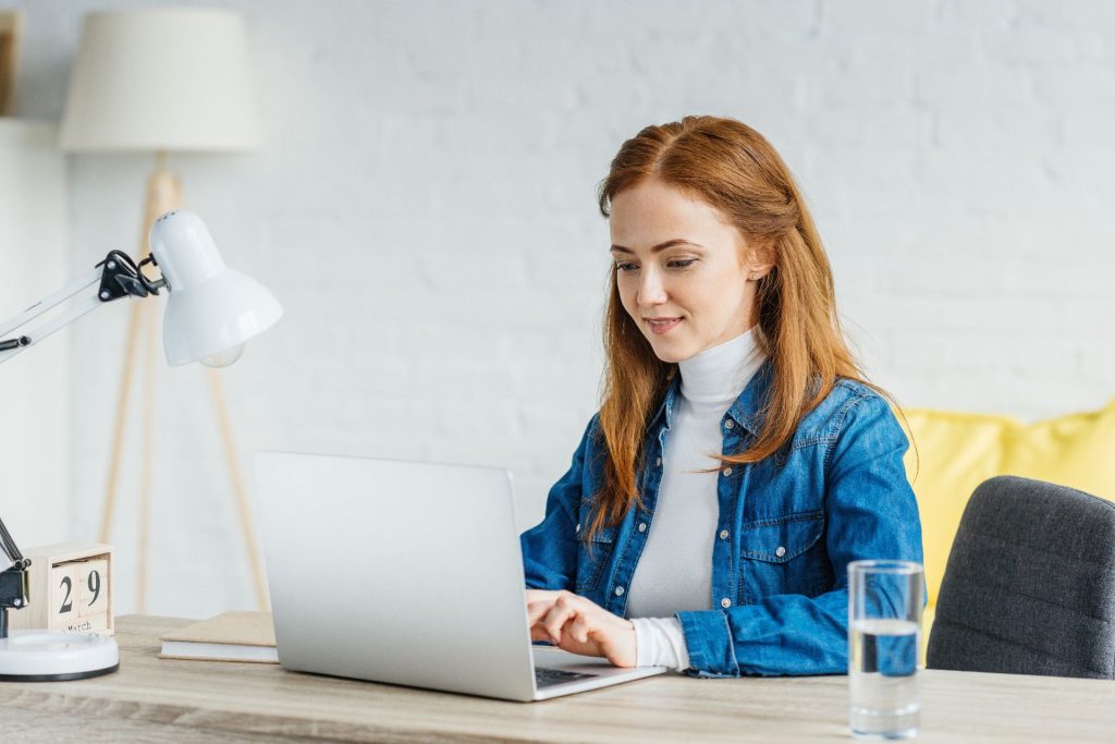 Kobieta siedzi przy biurku i pracuje przy laptopie