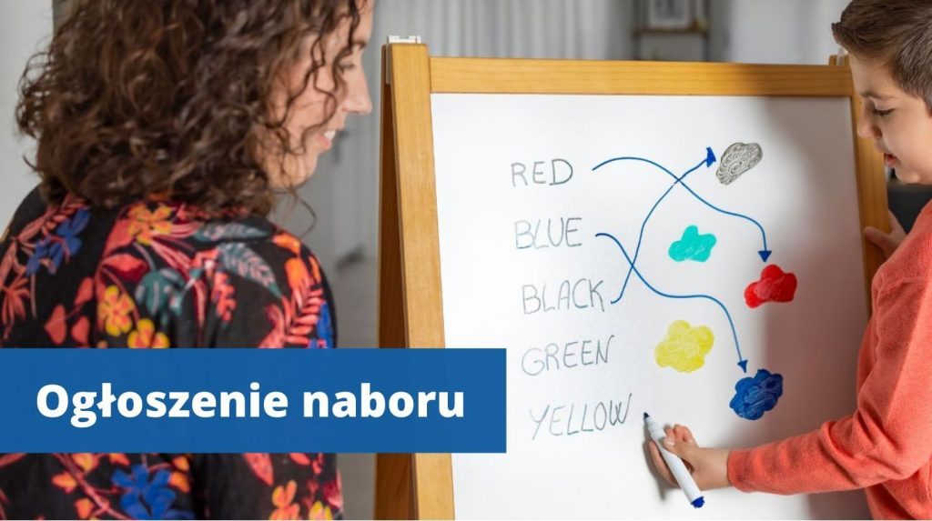 Przy tablicy stoi mały chłopiec i rysuje a obok nauczycielka