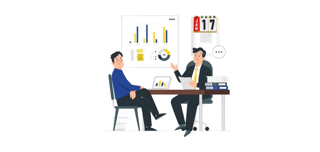 Dwóch mezczyzn siedzi przy biurku i pokazuja wykresy liczbowe