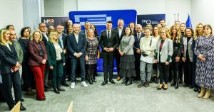 Grupa osób stojąca przed ścianką z Marszałkiem Województwa Małopolski.